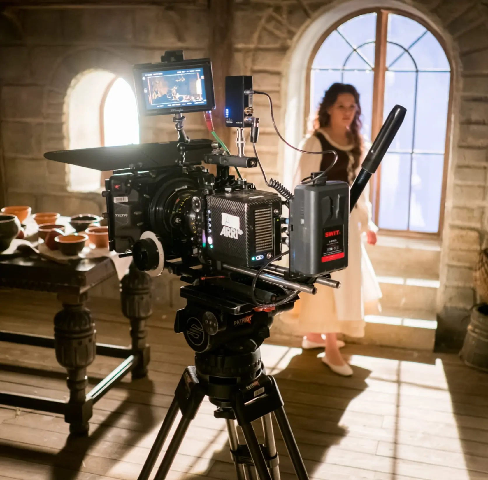 ARRI film camera on set with an actress in period costume behind